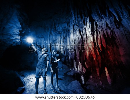 Young couple exploring huge cave with torches