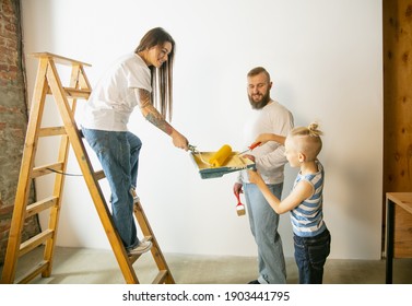 Young Couple, Family Doing Apartment Repair Together Themselves. Mother, Father And Son Doing Home Makeover Or Renovation. Concept Of Relations, Moving, Love. Preparing Wall For Wallpaper