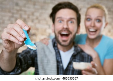 Young Couple Feeding Baby By Spoon. Photographed From Baby's Point Of View, Focus On Spoon.