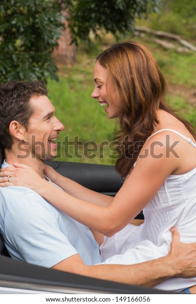 Young couple feeling romantic in back seat\
and laughing in a convertible in\
countryside