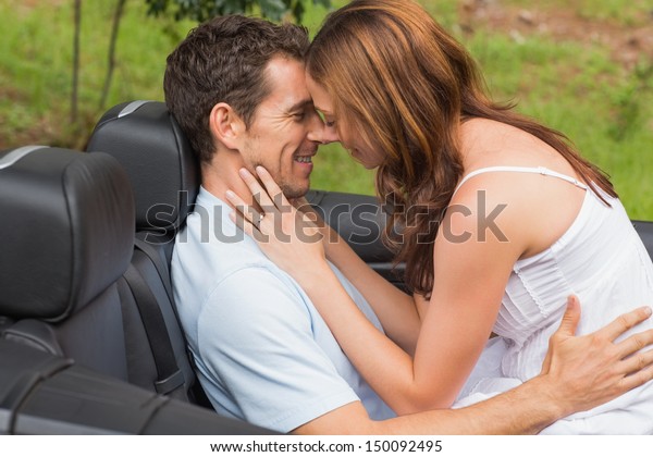 Young couple feeling romantic in back seat of\
convertible in\
countryside