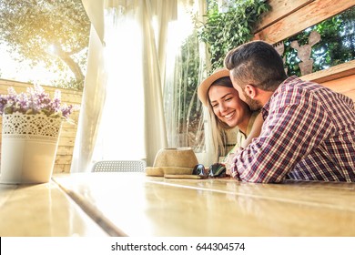 Young Couple Flirting At The First Date At Bar Cafe Table - Boyfriend And Girlfriend Enjoying Time Together In Summer Vacation - Travel And Love Concept - Focus On Woman Face - Warm Vintage Filter 