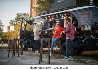 young couple flirting in front of truck with food while employee looking at them - Powered by Shutterstock