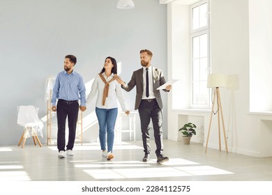 Young couple following a real estate agent who is giving them a tour around a big house, showing all the rooms and telling about all the advantages of living here. Buying house or apartment concept