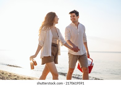 Young Couple Friend Family Man Woman 20s In White Clothes Drink Beer Hold Picnic Bag Refrigerator Hold Hands Walk Rest Together At Sunrise Over Sea Beach Outdoor Seaside In Summer Day Sunset Evening.