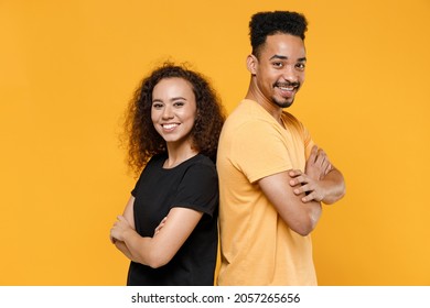 Young Couple Friends Together Team Family African Smiling Happy Man Woman 20s In Black T-shirt Standing Back To Back With Hands Crossed Folded Look Camera Isolated On Yellow Background Studio Portrait