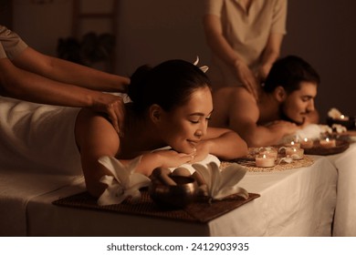 Young couple getting massage in dark spa salon - Powered by Shutterstock