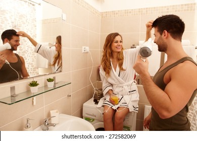 Young Couple Getting Ready In The Bathroom In The Morning, Drying Hair, Drinking Orange Juice.