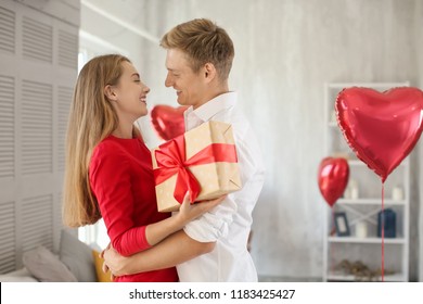 Young Couple With Gift Box Hugging At Home