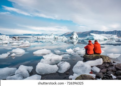 A Young Couple In Glacier Lagoon In Iceland.