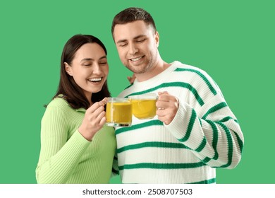 Young couple with glass cups of lemon tea on green background - Powered by Shutterstock