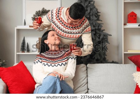 Young couple with glasses of mulled wine at home on Christmas eve