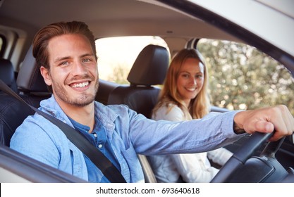 Young couple going on holiday in a car smiling to camera - Powered by Shutterstock