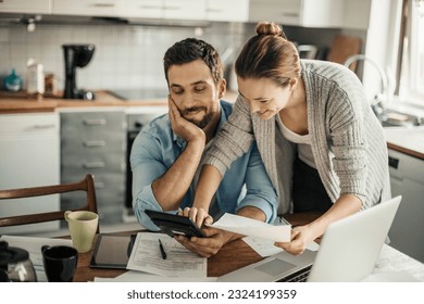 Young couple going over their bills at home in the kitchen - Powered by Shutterstock