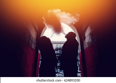 Young couple guy and girl are smoking couples from vape e-cigarettes on the street. Concept quit tobacco, give up cigarettes. - Powered by Shutterstock