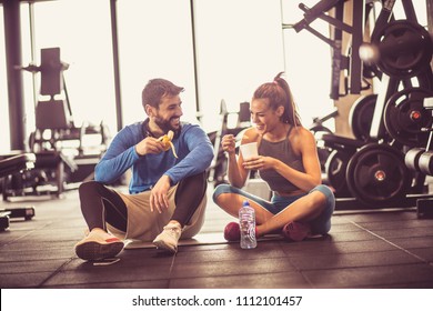 Young couple at gym eating healthy food after exercise.