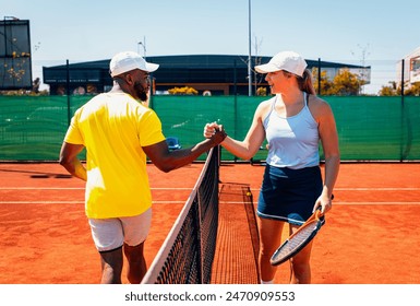 Young couple handsake across the net after a tennis match. - Powered by Shutterstock