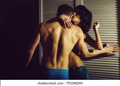 young couple of handsome macho man in pants with muscular body and pretty woman or sexy girl with naked chest at white wardrobe door