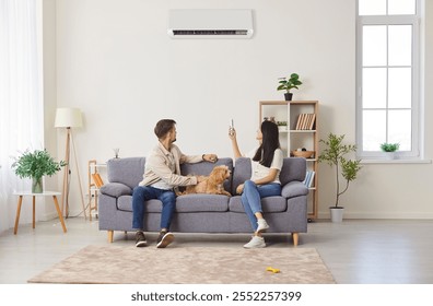 Young couple, happy family with dog on sofa switching on air conditioner, blowing warm, cold air room temperature control for optimal home environment, providing ideal climate control heating system