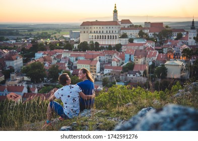 Young couple have romantic sunset over the city. Overlooking beautiful Mikulov castle, Chateau  from Saint Hill while sunset. Wine region. South Moravia, Czech Republic.
