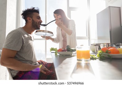 Young Couple Having Breakfast, Hispanic Man Eat Asian Woman Cooking Food Kitchen Modern Apartment Interior