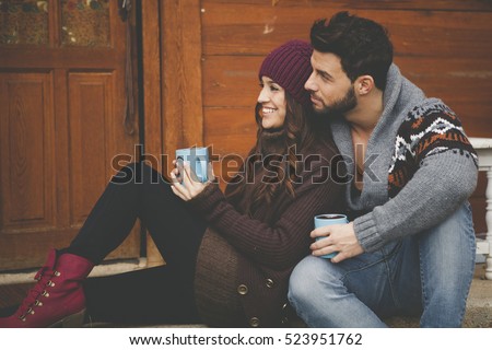 Young couple having breakfast in a romantic cabin outdoors in winter.