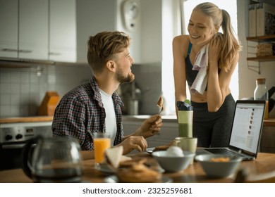 Young couple having breakfast together in the morning and using a laptop - Powered by Shutterstock