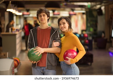 Young Couple Having Fun In Bowling Alley.  Portrait Of Smiling Couple. Holding A Bowler. 