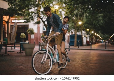 Young Couple Having Fun In The City On Bicycle. Happy Young Couple On Bike Ride.