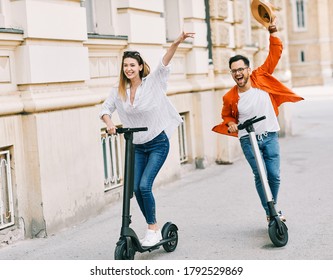 Young Couple Having Fun Driving Electric Scooter Through The City