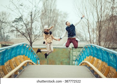 Young couple having fun jumping on bridge.