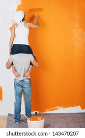 Young Couple Is Having Fun Painting A Wall