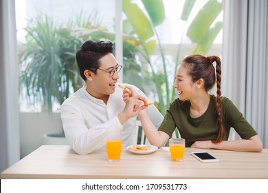 Young couple having fun while having breakfast  feeding each other