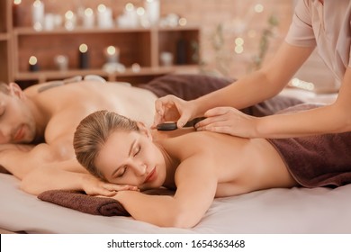 Young couple having massage with hot stones in spa salon