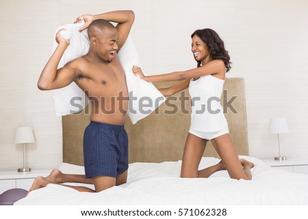 Young couple having pillow fight on the bed
