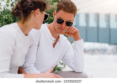 Young Couple Having Problems In Their Relationship. Man And Woman Friends In Sunglasses Sitting Bench In City Unhappy Emotions. Relationships Problem.