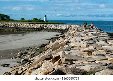 Young Couple Hiking Along Rocky Breakwater Towards Black Rock Harbor Light Connecting To Fayerweather Island In Bridgeport, Connecticut. It Is A Favorite Challenge For Many Tourists To Seaside Park.