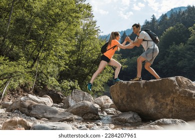 Young couple hiking along the rocky shore of a mountain river, exploring beautiful nature. Concept of an active vacation. - Powered by Shutterstock