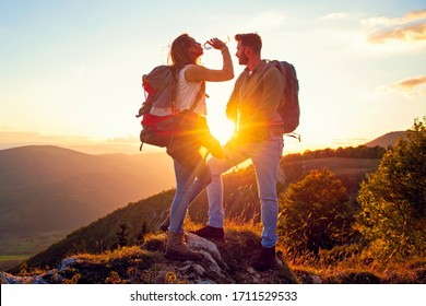 Young Couple Hiking On The Peak of Mountain drinking water