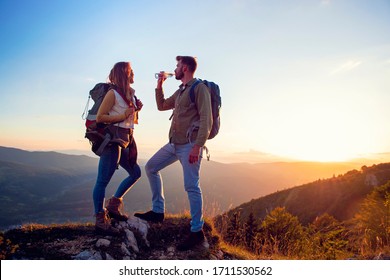 Young Couple Hiking On The Peak Of Mountain Drinking Water