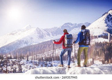 Young Couple Hiking Outside In Sunny Winter Mountains