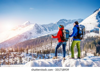 Young Couple Hiking Outside In Sunny Winter Mountains