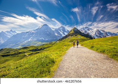 Young couple hiking in panorama trail leading to Kleine Scheidegg from Mannlichen with Eiger, Monch and Jungfrau mountain (Swiss Alps) in the background, Berner Oberland, Grindelwald, Switzerland.  