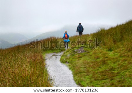A young couple hiking in Scotland, misty hiking path. Foggy day un UK. 