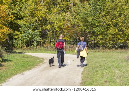Young couple are hiking through the forest with their pet dogs