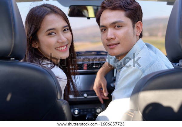 Young couple in his car, happy\
to drive on a country road. Happy young women and young men in\
car