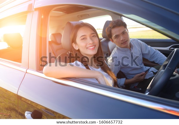 Young couple in his car, happy\
to drive on a country road. Happy young women and young men in\
car
