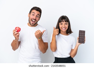 Young Couple Holding Chocolate And Apple Isolated On White Background Giving A Thumbs Up Gesture With Both Hands And Smiling