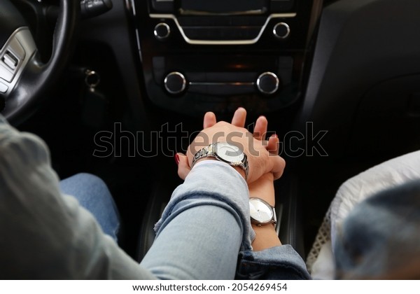 Young couple holding hands in\
car