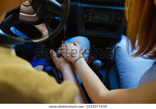 Young\
couple holding hands inside the car on the gear stick. Romantic\
couple holding hands in the car while\
driving.